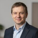 Портрет уверенного российского бизнесмена с дружелюбным взглядом на размытом нейтральном фоне в студии
