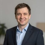 Портрет уверенного российского бизнесмена с дружелюбным взглядом на размытом нейтральном фоне в студии
