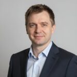 Портрет уверенного российского бизнесмена с дружелюбным взглядом на размытом нейтральном фоне в студии